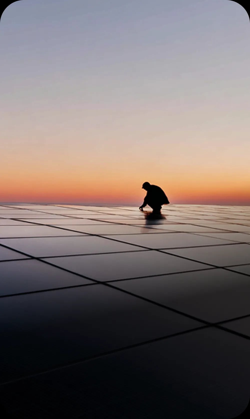 Worker silhouette on solar panels at sunset